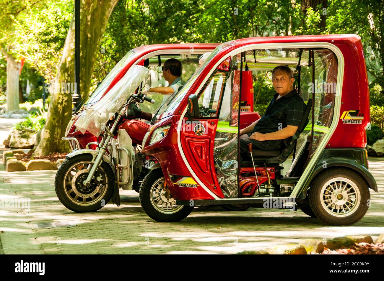 Trishaw drivers waiting for some passengers in the shade in Shanghai’s Fuxing Park. Stock Photo