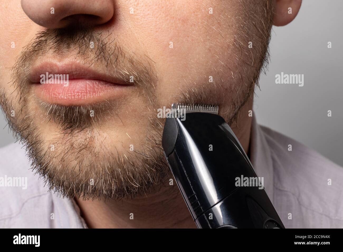 A man shaves his beard with a trimmer razor. Modeling beard, masculine