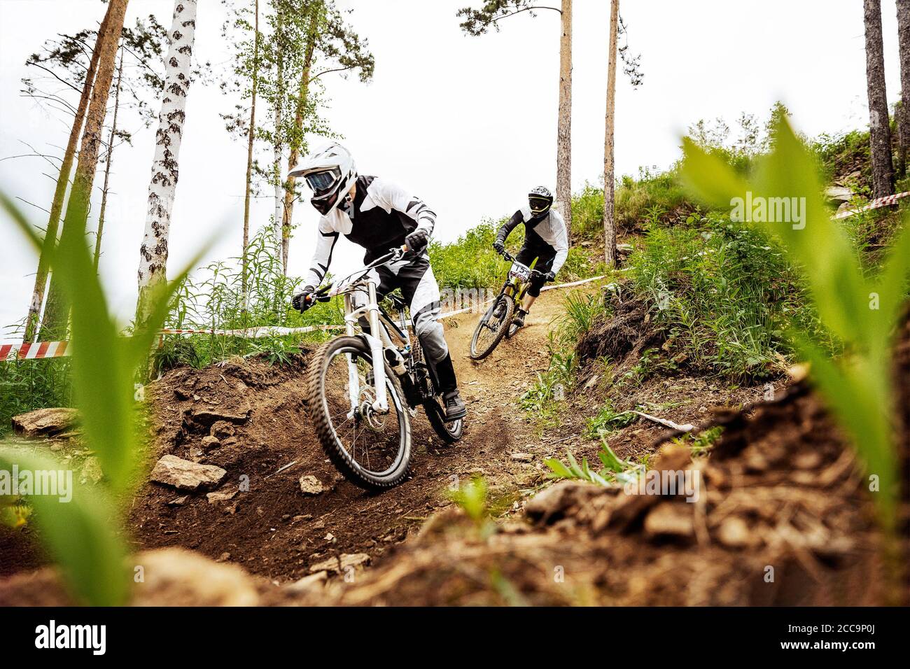 two downhill mountain biker on forest trail. rides competition DH Stock Photo