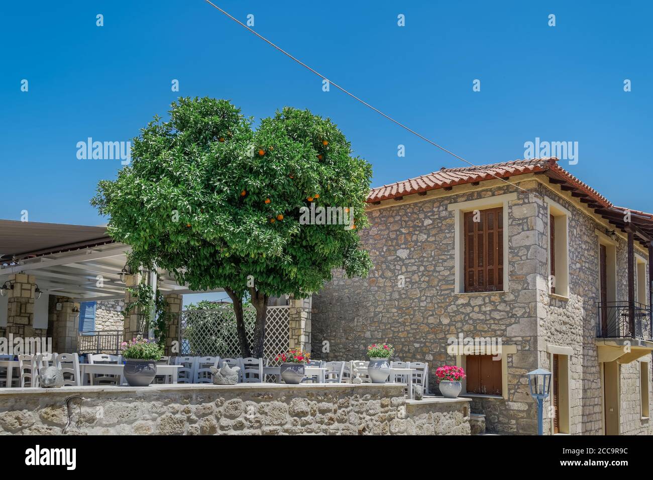 Chalkidiki, Greece empty tavern wooden chairs & tables after covid-19 measures. Restaurant outdoor seating area without customers in Athytos village. Stock Photo