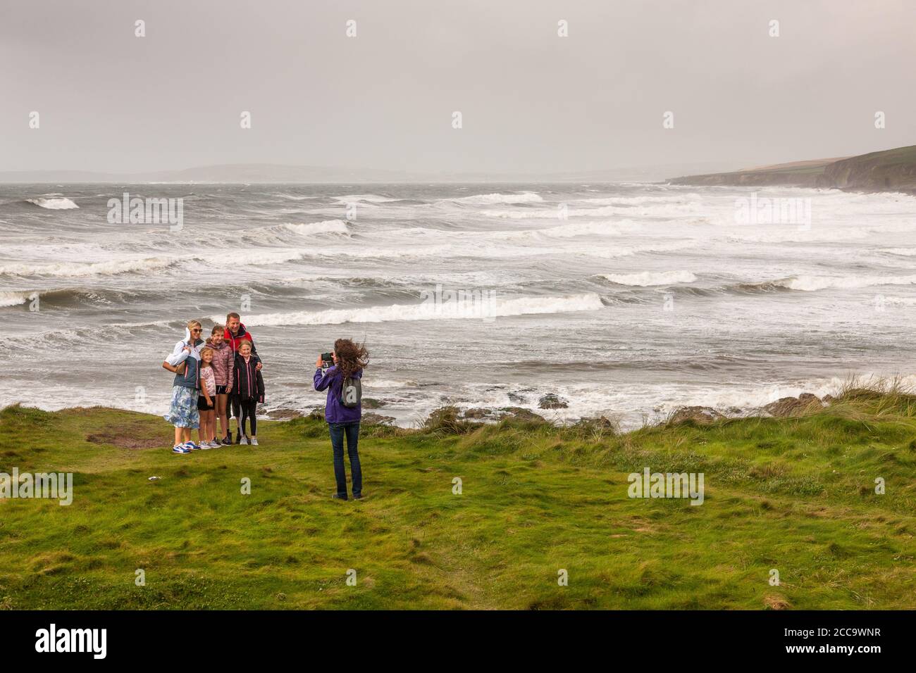 Garrettstown, Cork, Ireland. 20th August, 2020. French visitor Axeller Josselin takes a picture for the Madigan family from Kilkenny with a backdrop of the Wild Atlantic Way in the aftermath of Storm Ellen at Garrettstown, Co. Cork, Ireland. - Credit; David Creedon / Alamy Live News Stock Photo