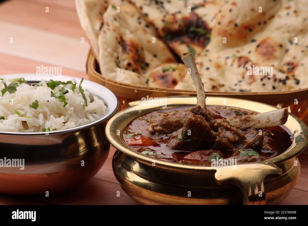 Mutton curry Served with naan or bread and jeera rice over wooden background. Stock Photo