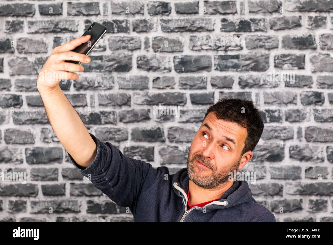 Male with a beard taking a selfie with his smartphone in front of a ...