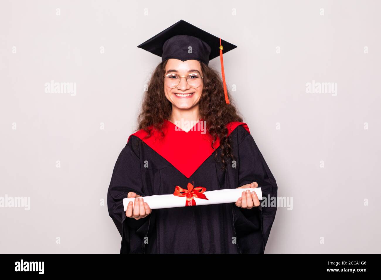 Beautiful college graduate wearing cap and gown holding diploma isolated on  white background Stock Photo - Alamy