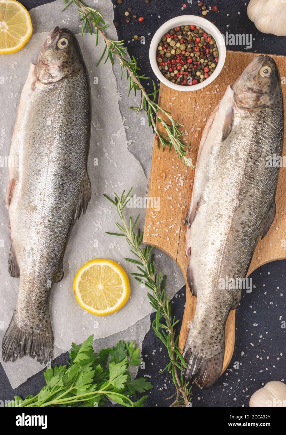 Fresh raw trout with rosemary, garlic, pepper, salt and lemon. Healthy Mediterranean food and dieting concept, top view, flat lay. Ready for a grill. Stock Photo