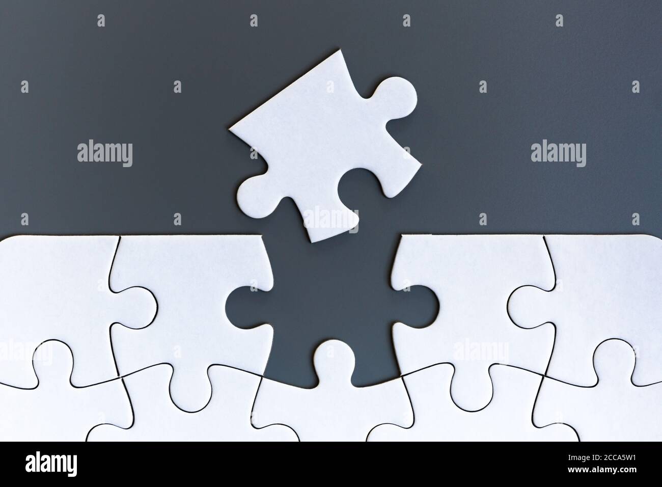 White jigsaw puzzle pieces on gray background Stock Photo