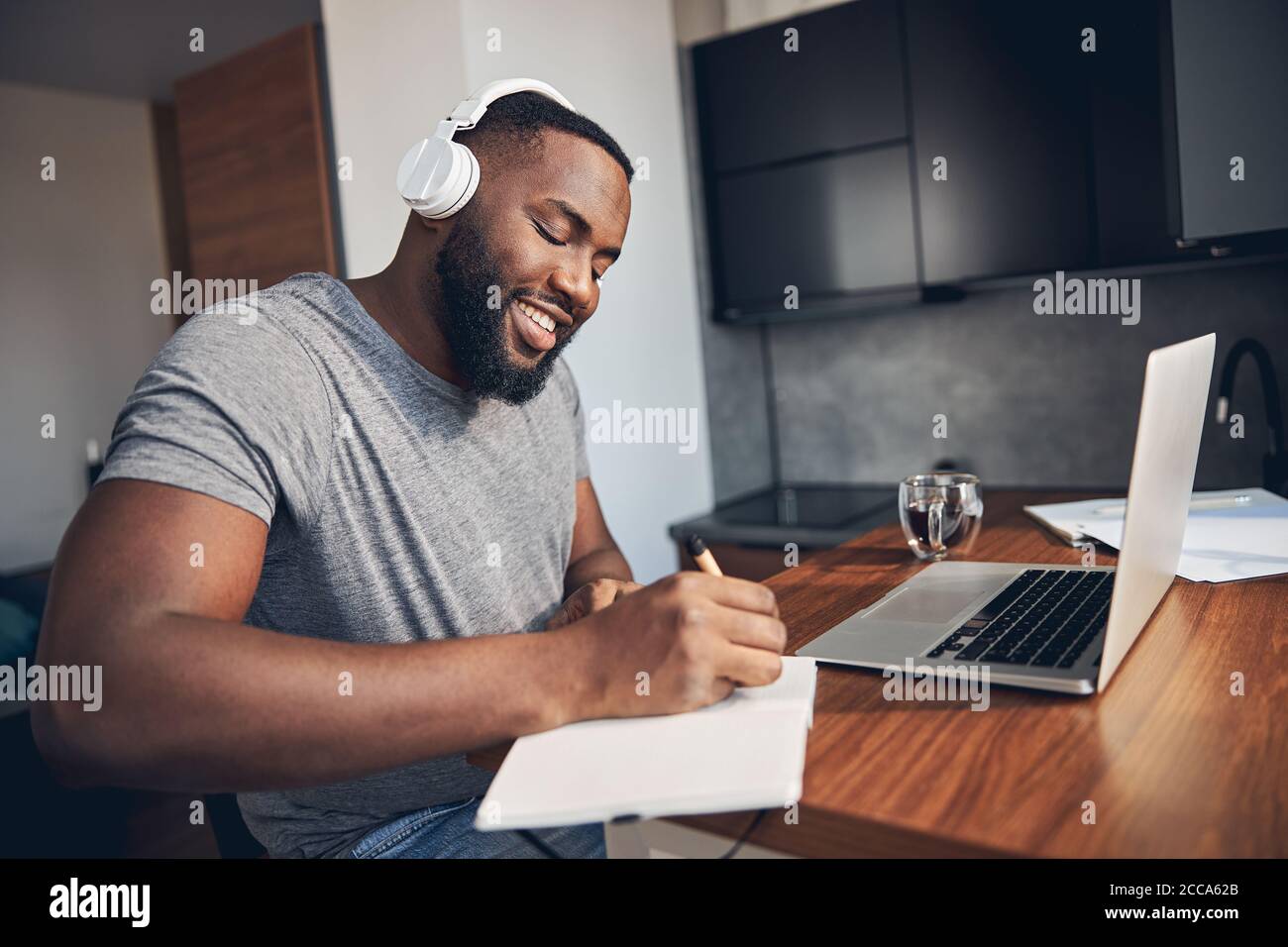 Cheerful bearded man making notes in notebook Stock Photo