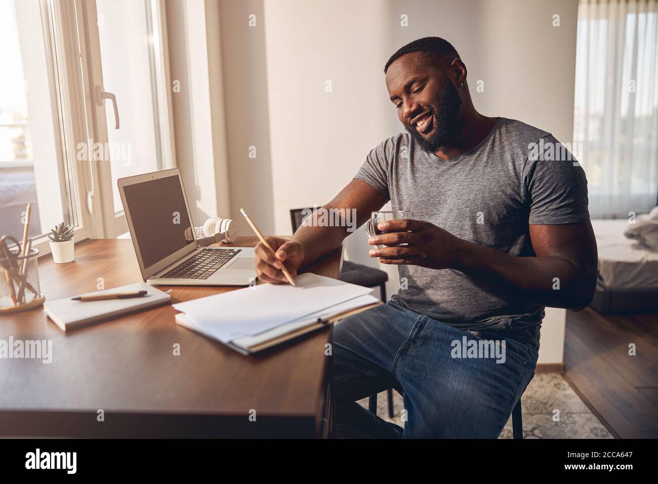 Positive delighted male person making notes during talk Stock Photo