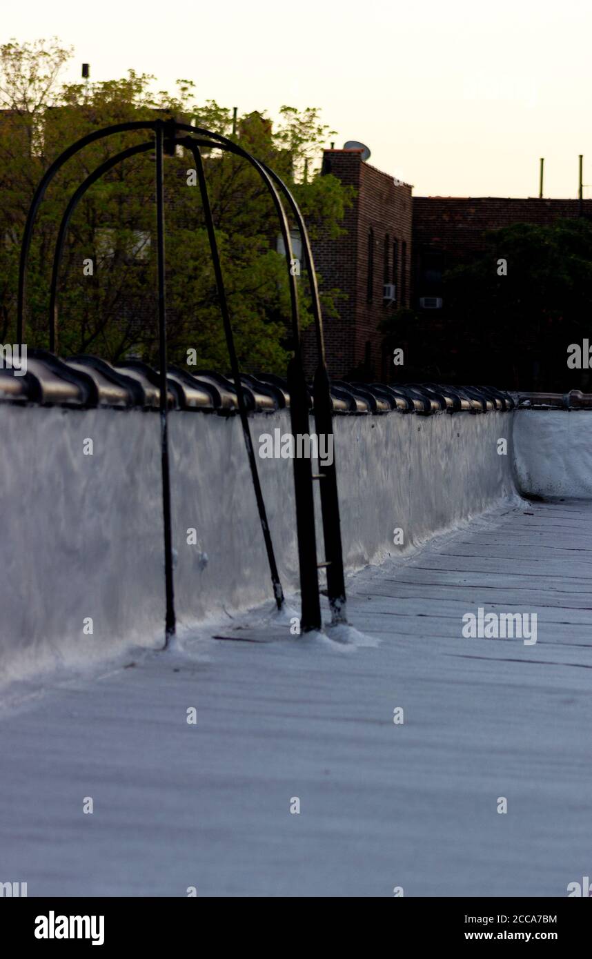 The curved end of a fire escape ladder arching over ceramic cap tiles