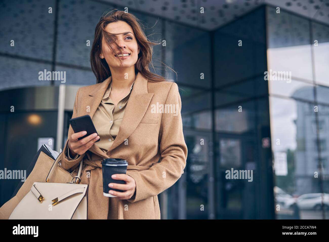 Smiling woman holding a paper coffee cup Stock Photo