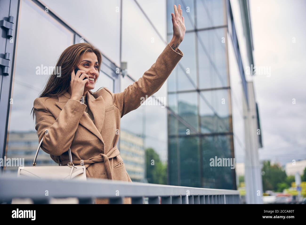 Happy lady with a raised arm standing outdoors Stock Photo