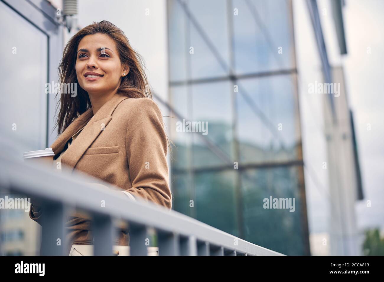 Good-looking lady with a paper cup standing outdoors Stock Photo