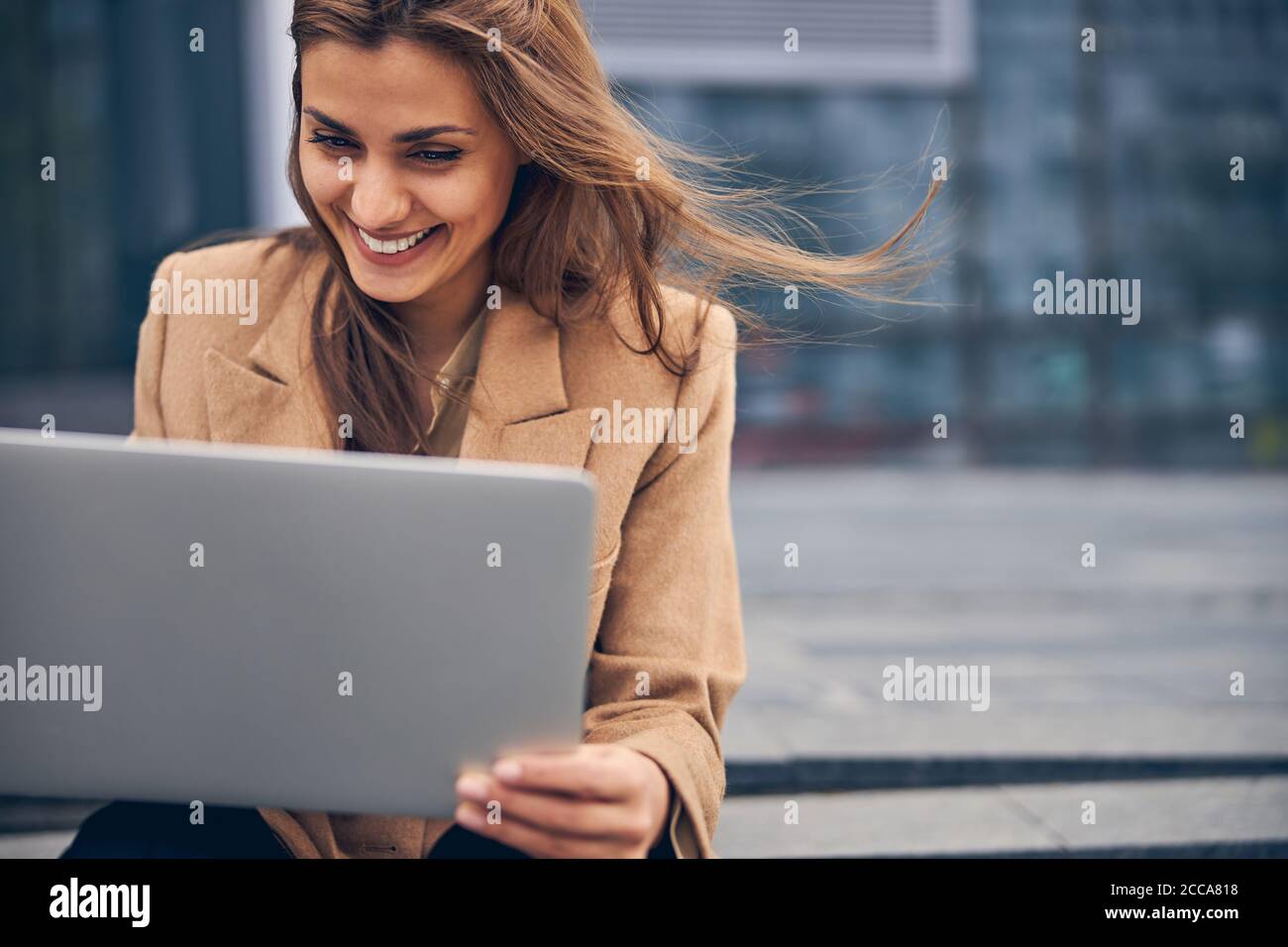 High-spirited young woman using her laptop outside Stock Photo - Alamy