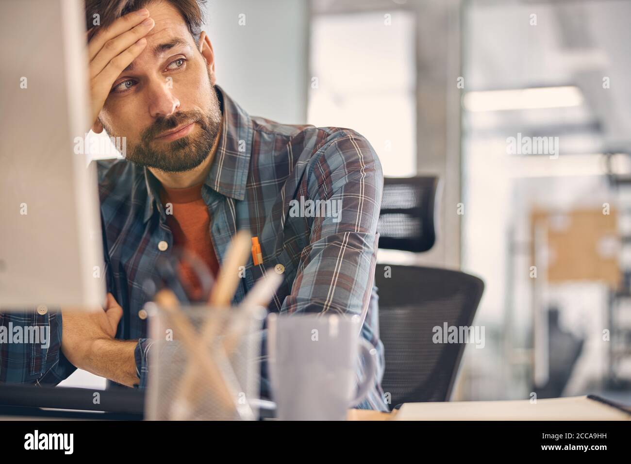 Tired young man sitting at the table in office Stock Photo