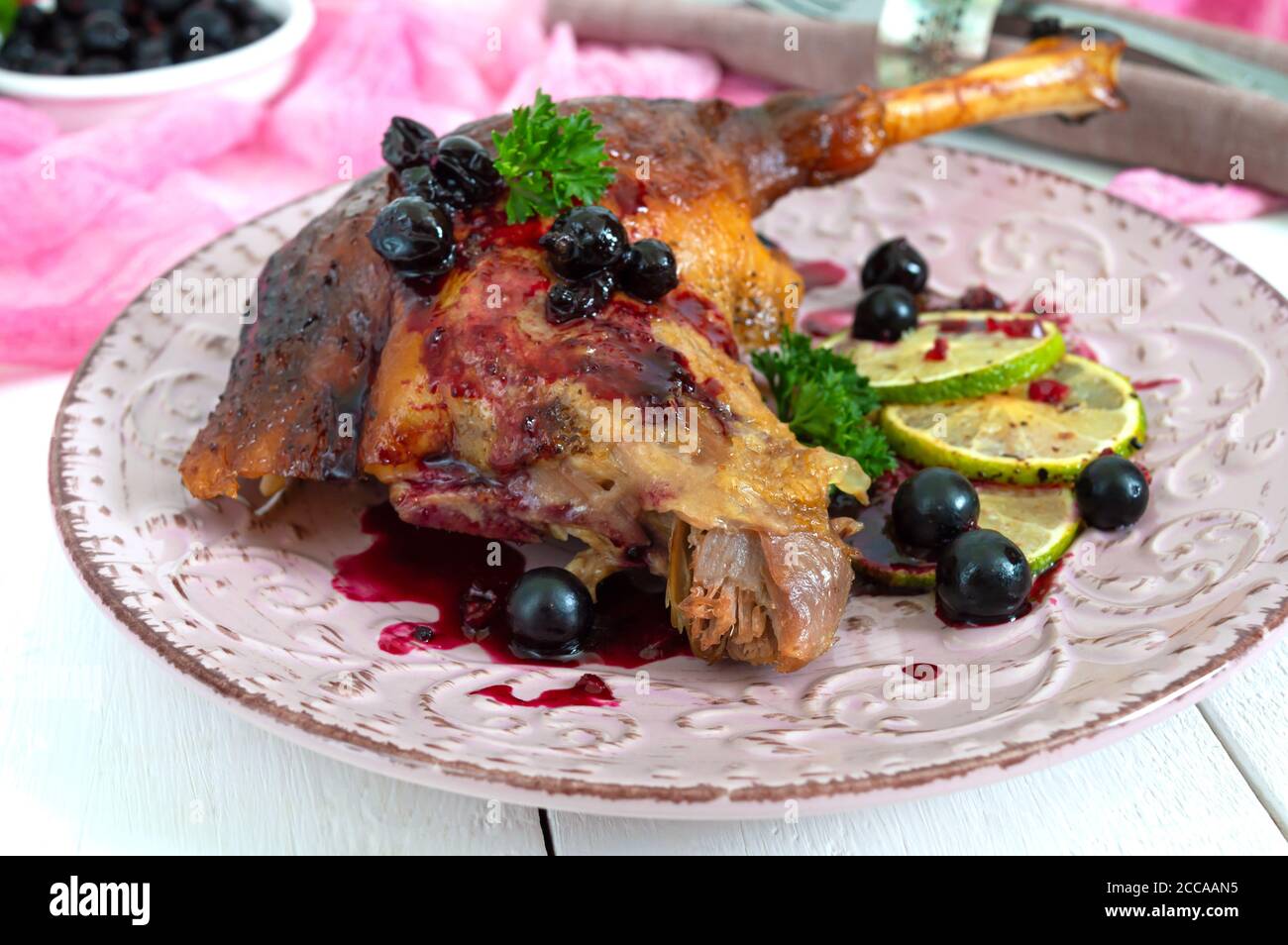 Baked duck leg confit with berry sauce on a plate. Holiday menu. Stock Photo