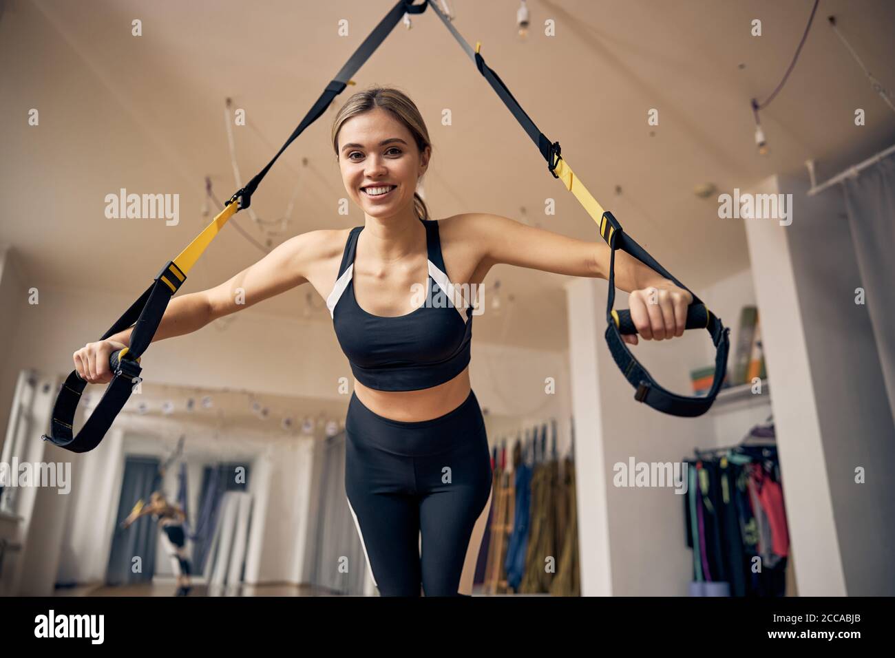 Sportswoman performing a chest press with a suspension trainer Stock