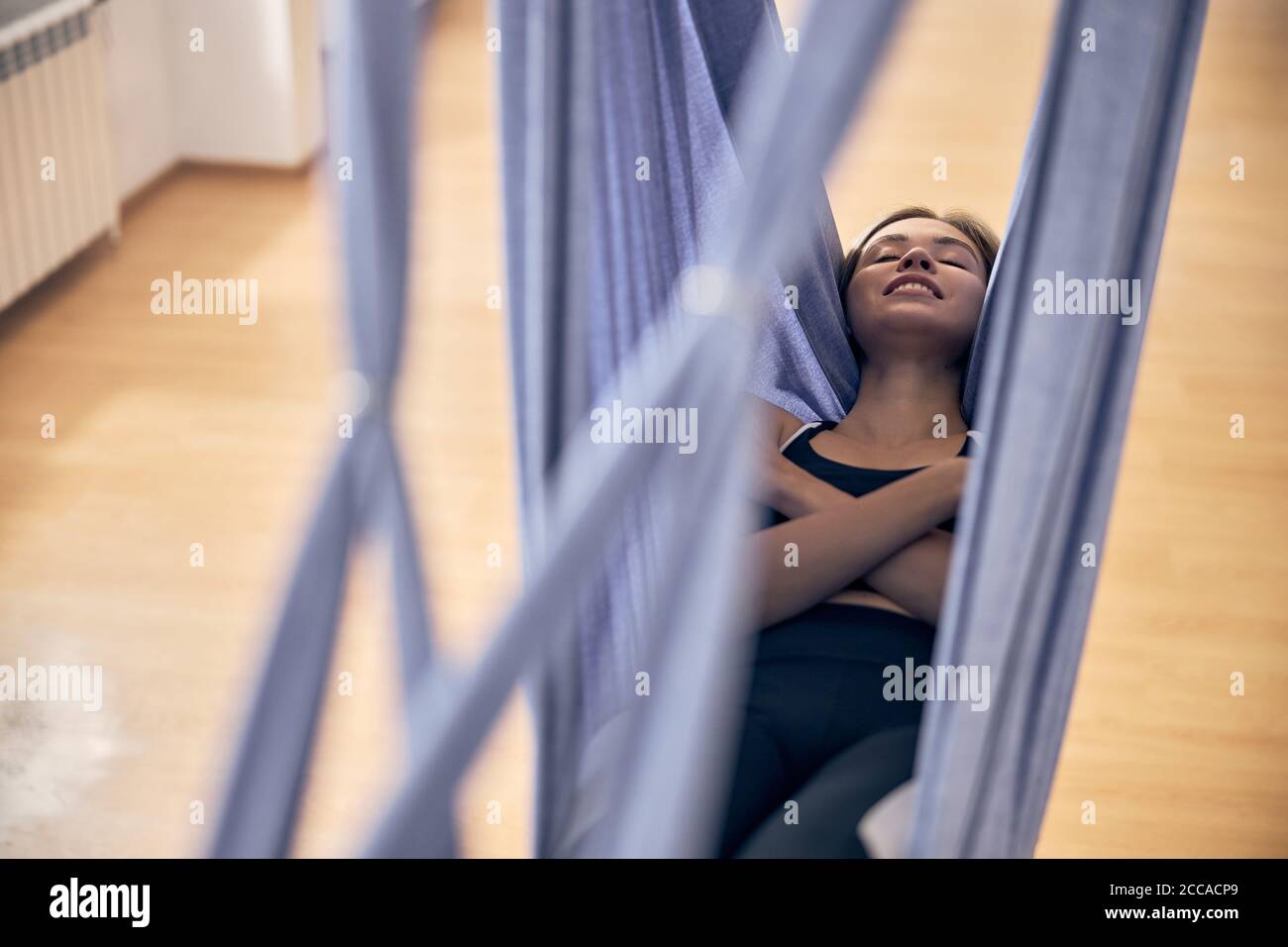 Woman relaxing in a hammock in an aerial yoga class Stock Photo