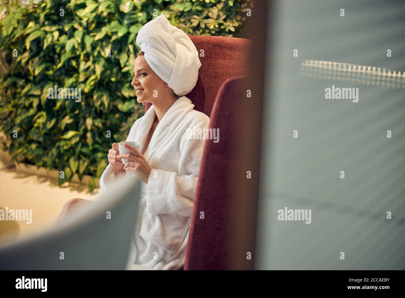 Pleased lady with a cup in her hands staring away Stock Photo