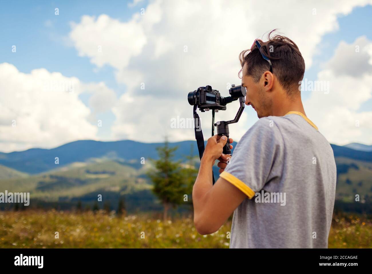 Videographer filming Carpathian mountains landscape. Man using steadicam and camera to make footage. Video shoot Stock Photo