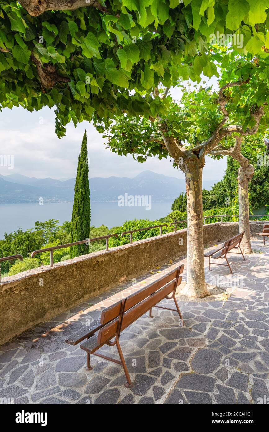 Empty bench in the shade of plane trees with a view of Lake Garda at the church of Albisano, Veneto, Italy Stock Photo