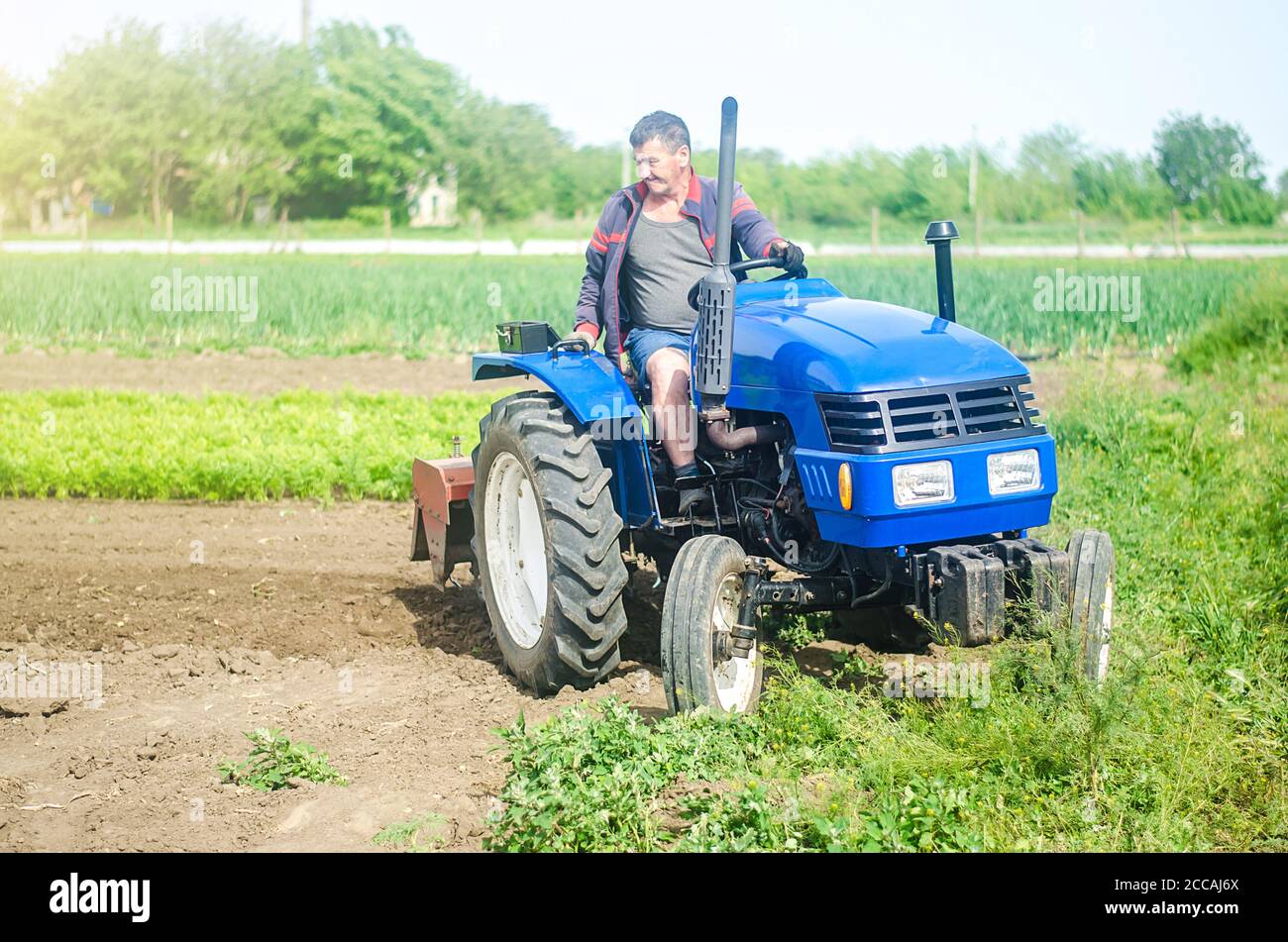 A farmer drives a tractor while working on a farm field. Loosening