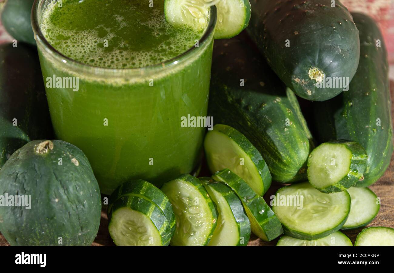 Juice and fresh fruits of green cucumber (Cucumis sativus). Wood background. Vegetables for salads. Detox juice. Green juice. Antioxidant drink. Brazi Stock Photo