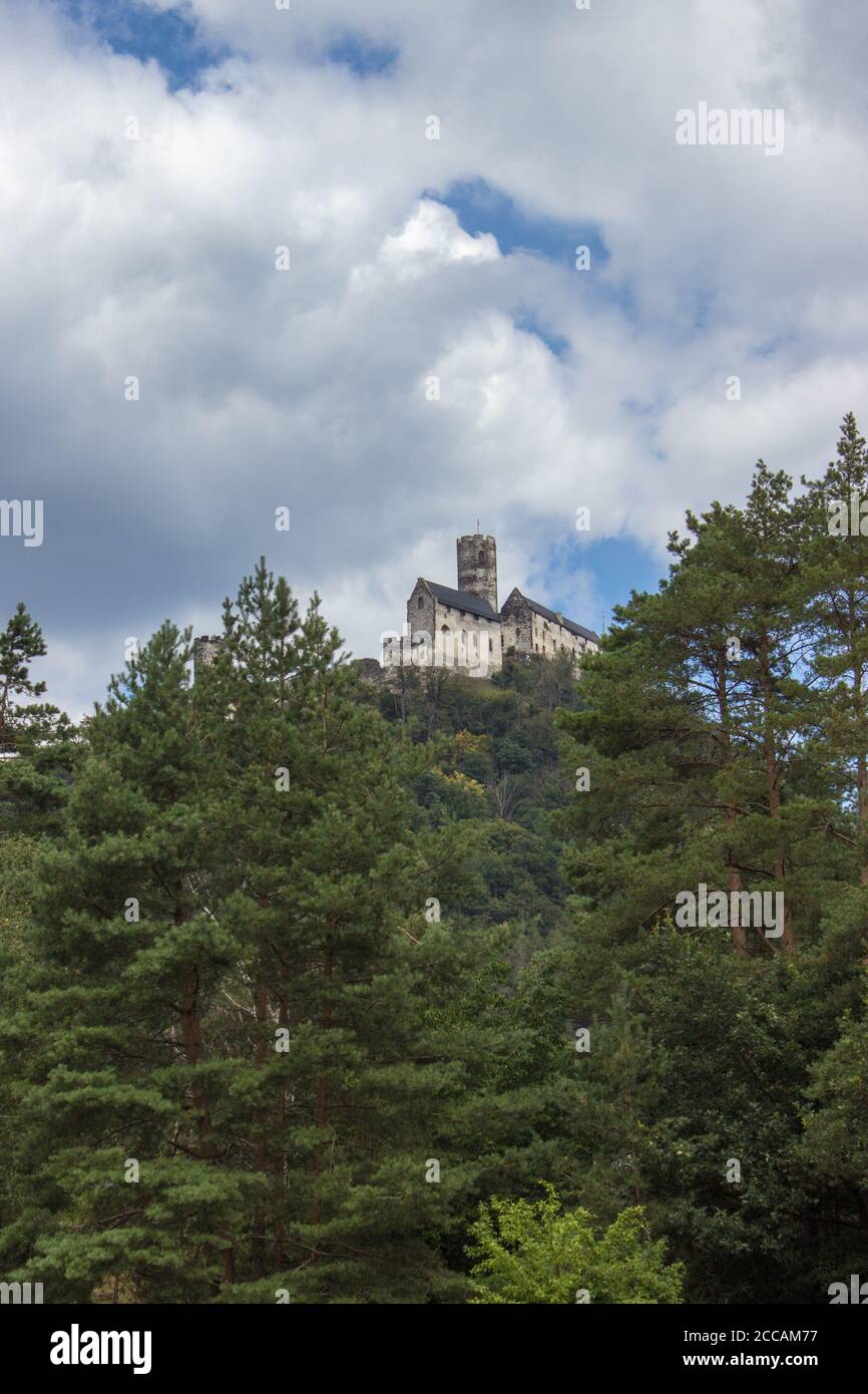 Panoramic view of Bezdez castle in the Czech Republic. In the foreground there are trees, in the background is a hill with castle and there are a whit Stock Photo