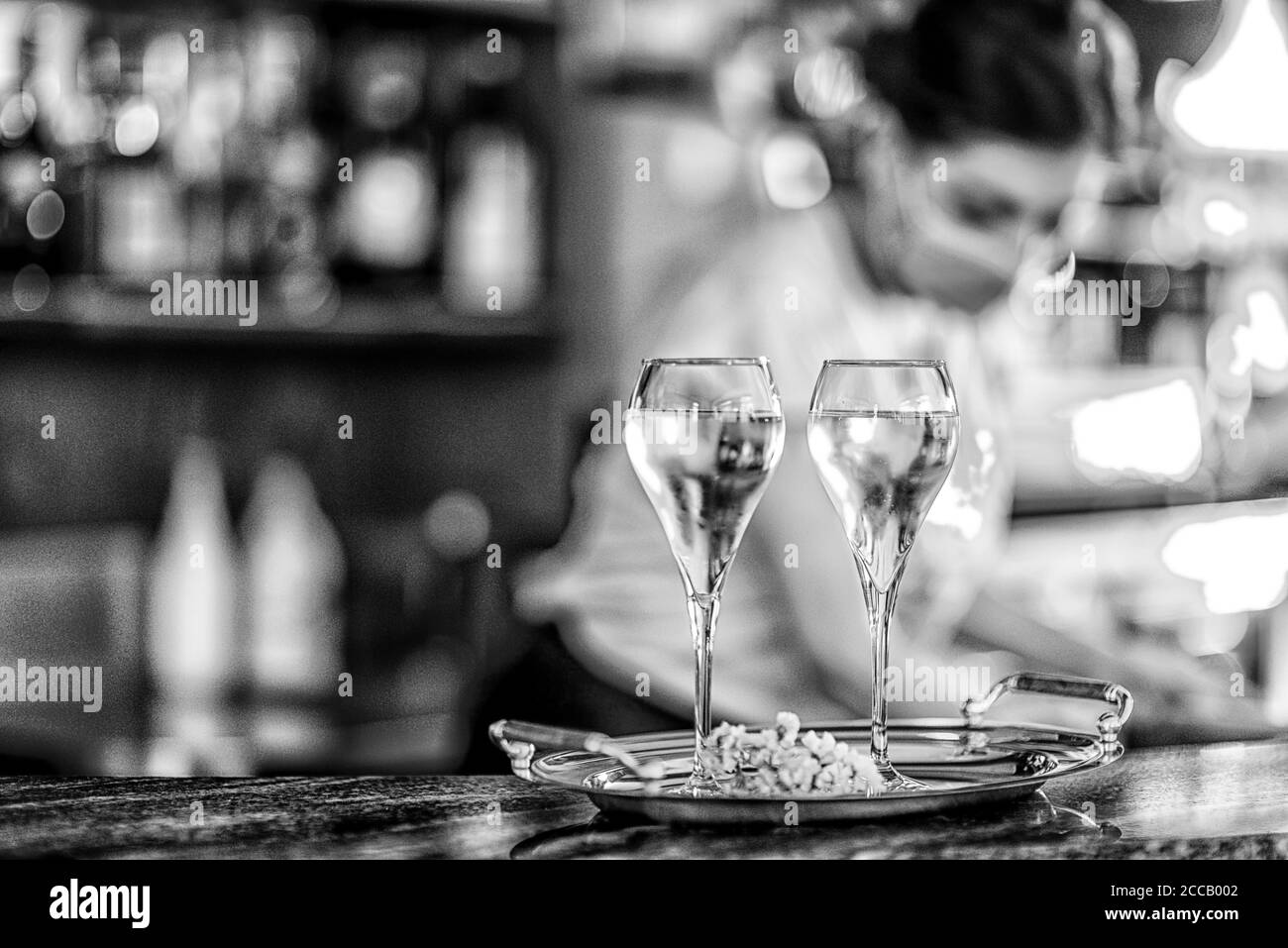 Young female italian bartender wearing face mask pouring white wine in two glasses for celebraion Stock Photo