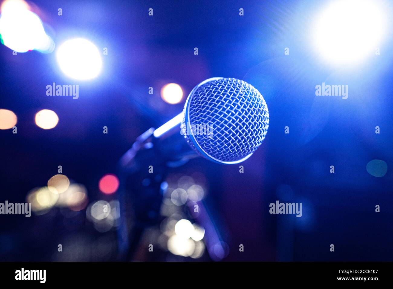 round microphone in the rays of multi-colored lamps on the concert stage Stock Photo