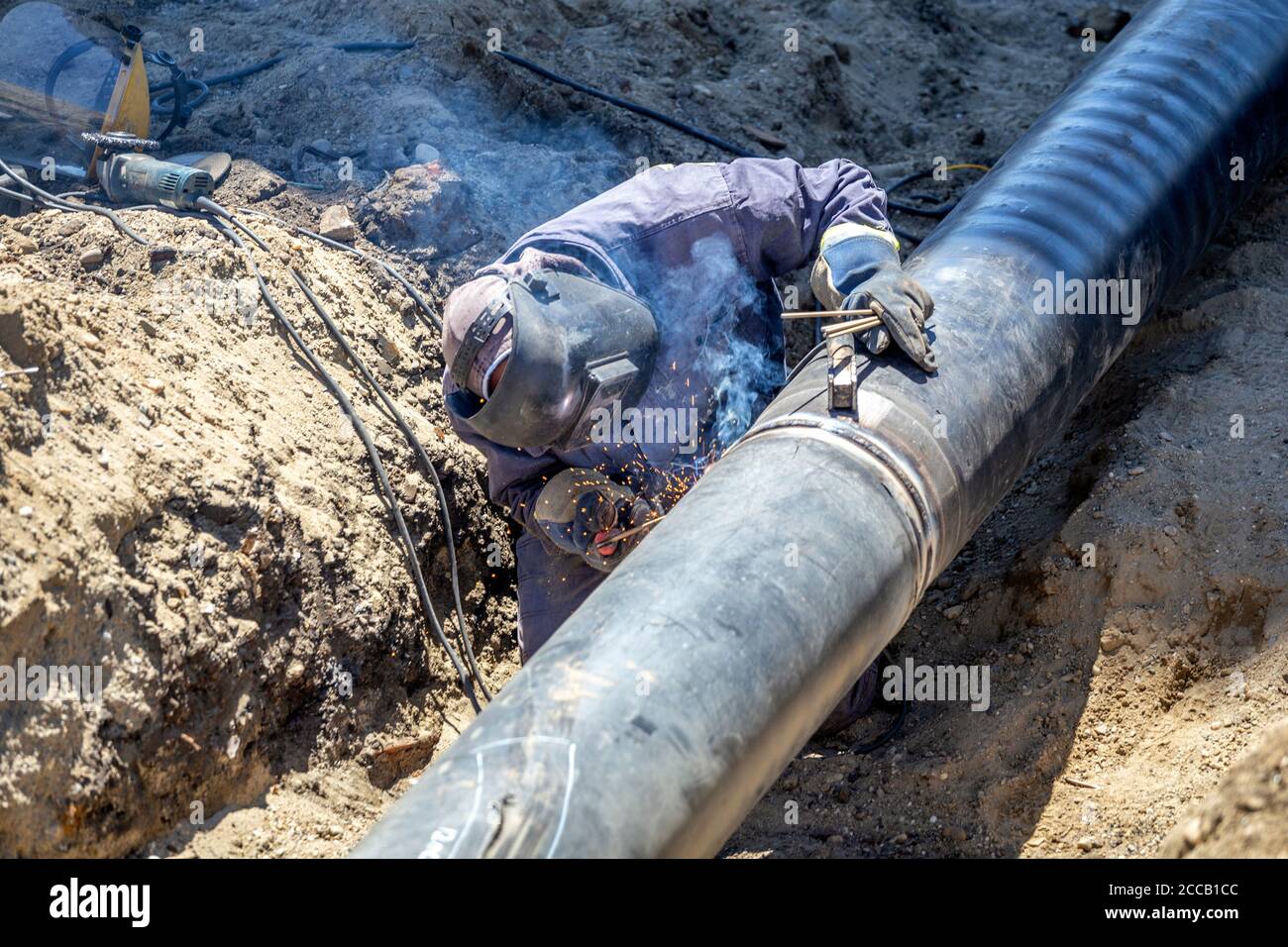 Outdoor shielded metal arc welding at pipeline construction site. Stock Photo