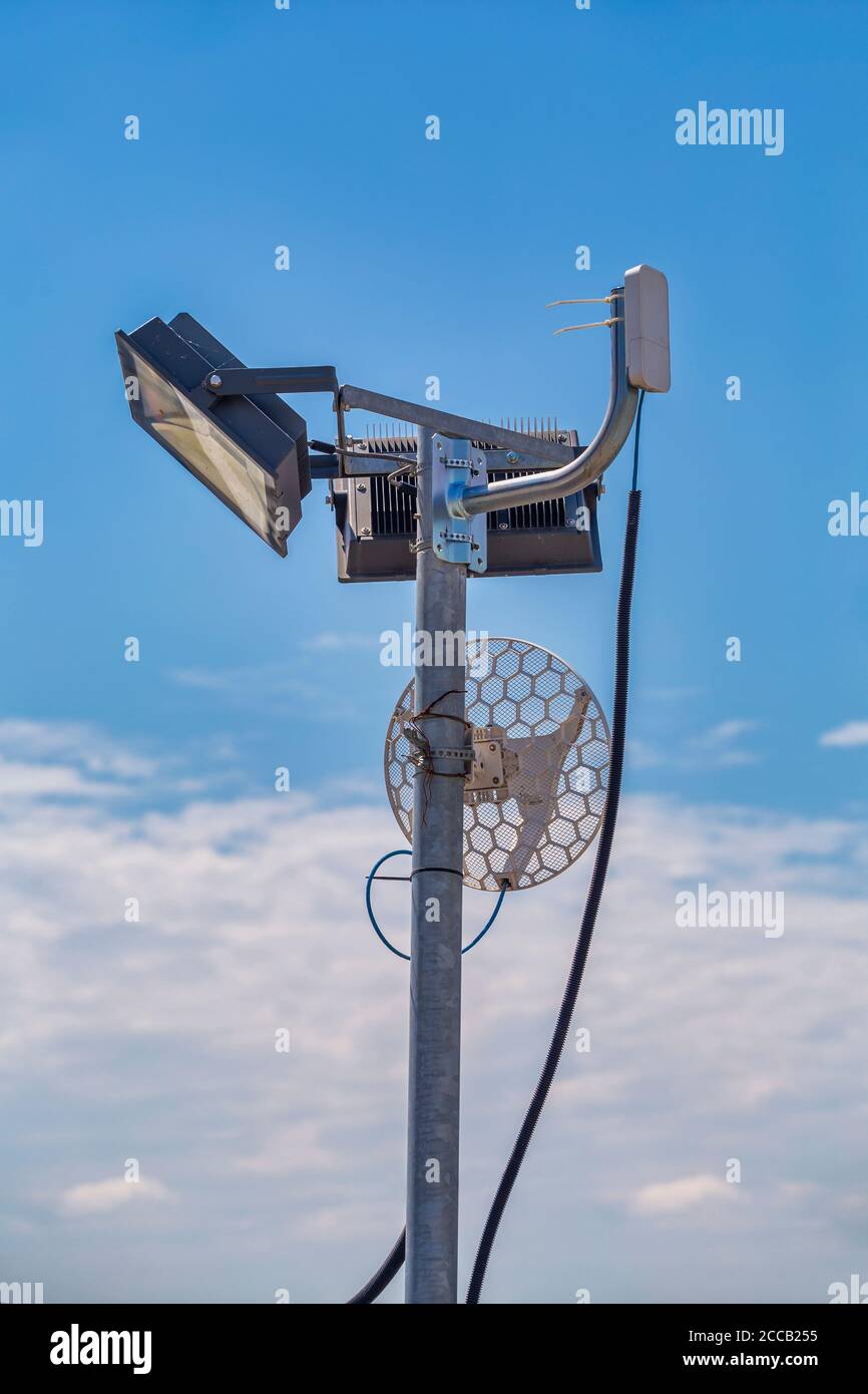 Wifi antenna outdoor on a metal light pole with blue sky background. Stock Photo