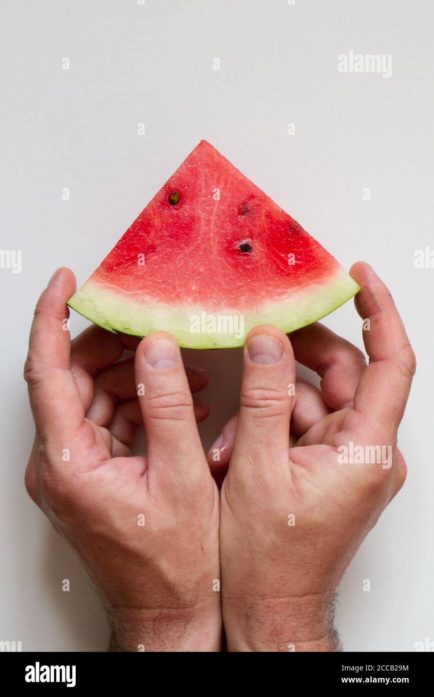Male hahds holding slice of ripe watermelon on white background, top view Stock Photo