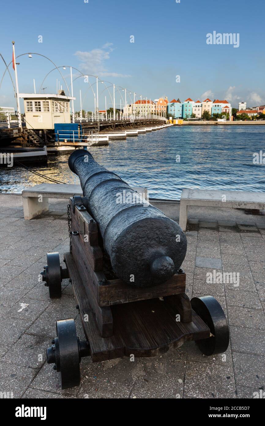 Historic cannons guard the Punda waterfront of Willemstad, overlooking Otrobanda across the Santa Anna Bay. At left is the Queen Emma swinging bridge Stock Photo
