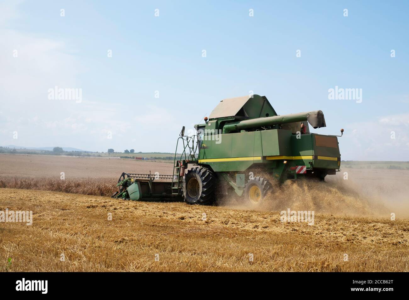Harvesting wheat in autumn field. A modern green harvester combine working Stock Photo