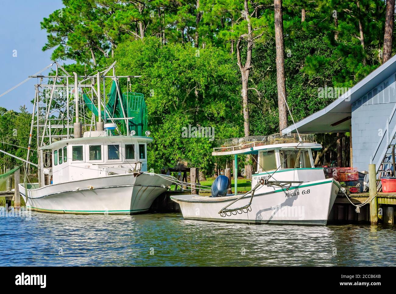An oyster boat and shrimp boat are docked in front of a home on Fowl