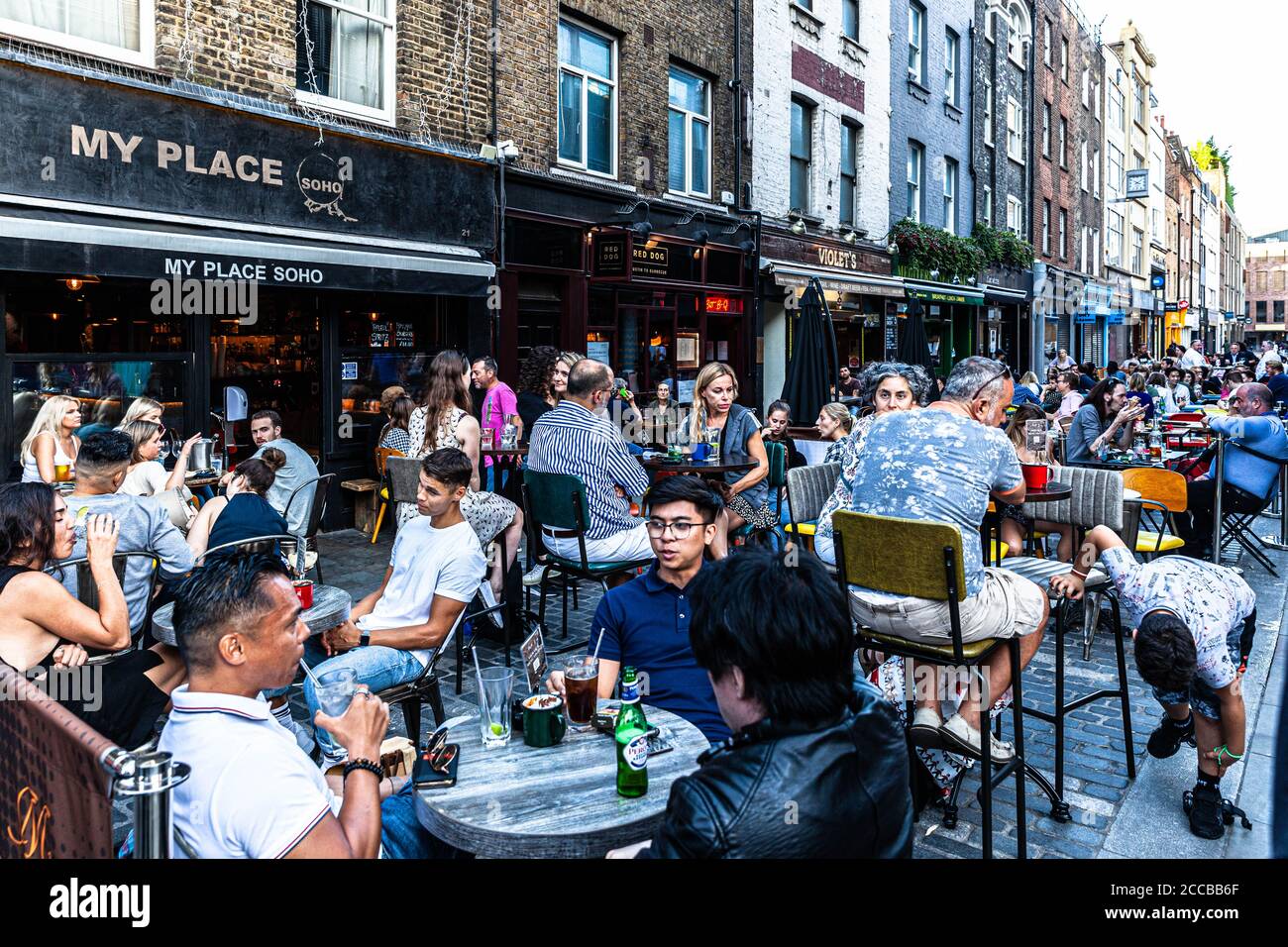 Customers dining al fresco on a pedestrianised street, Berwick Street, Soho, London, UK. Stock Photo