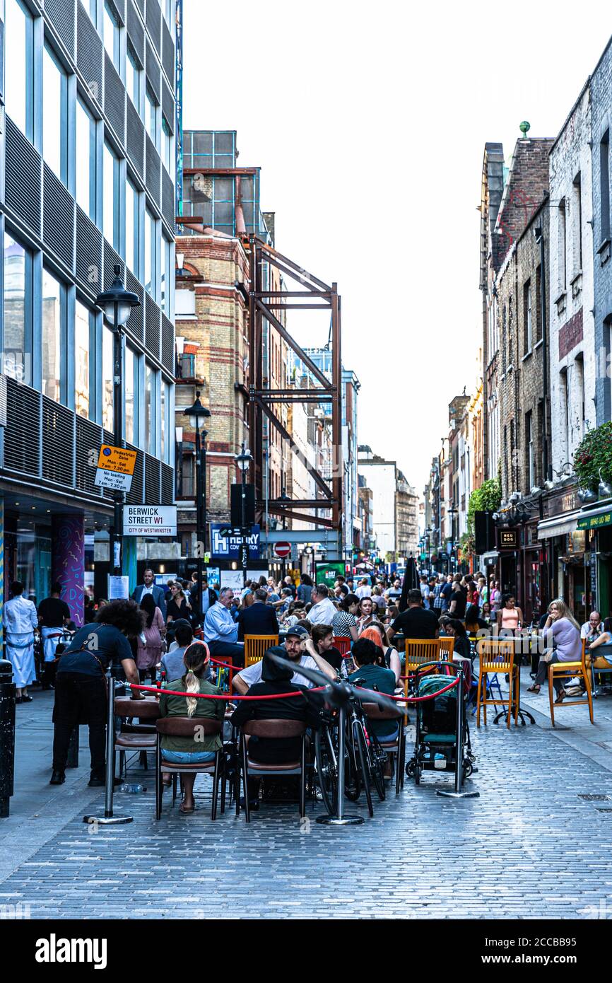 Customers dining al fresco on a pedestrianised street, Berwick Street, Soho, London, UK Stock