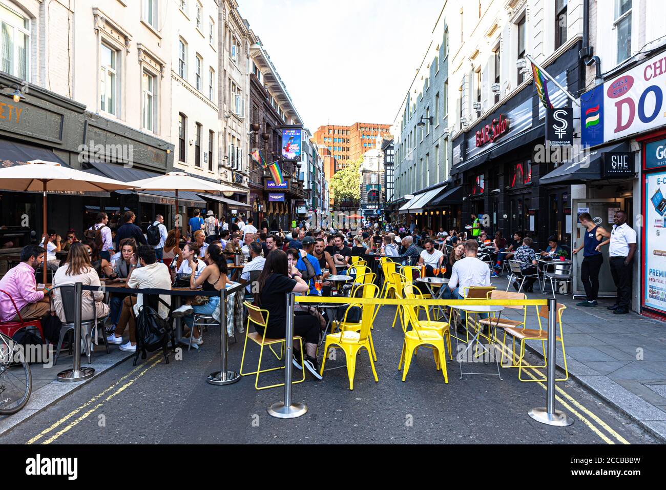 Customers dining al fresco on a pedestrianised street, Old Compton Street, Soho, London, UK