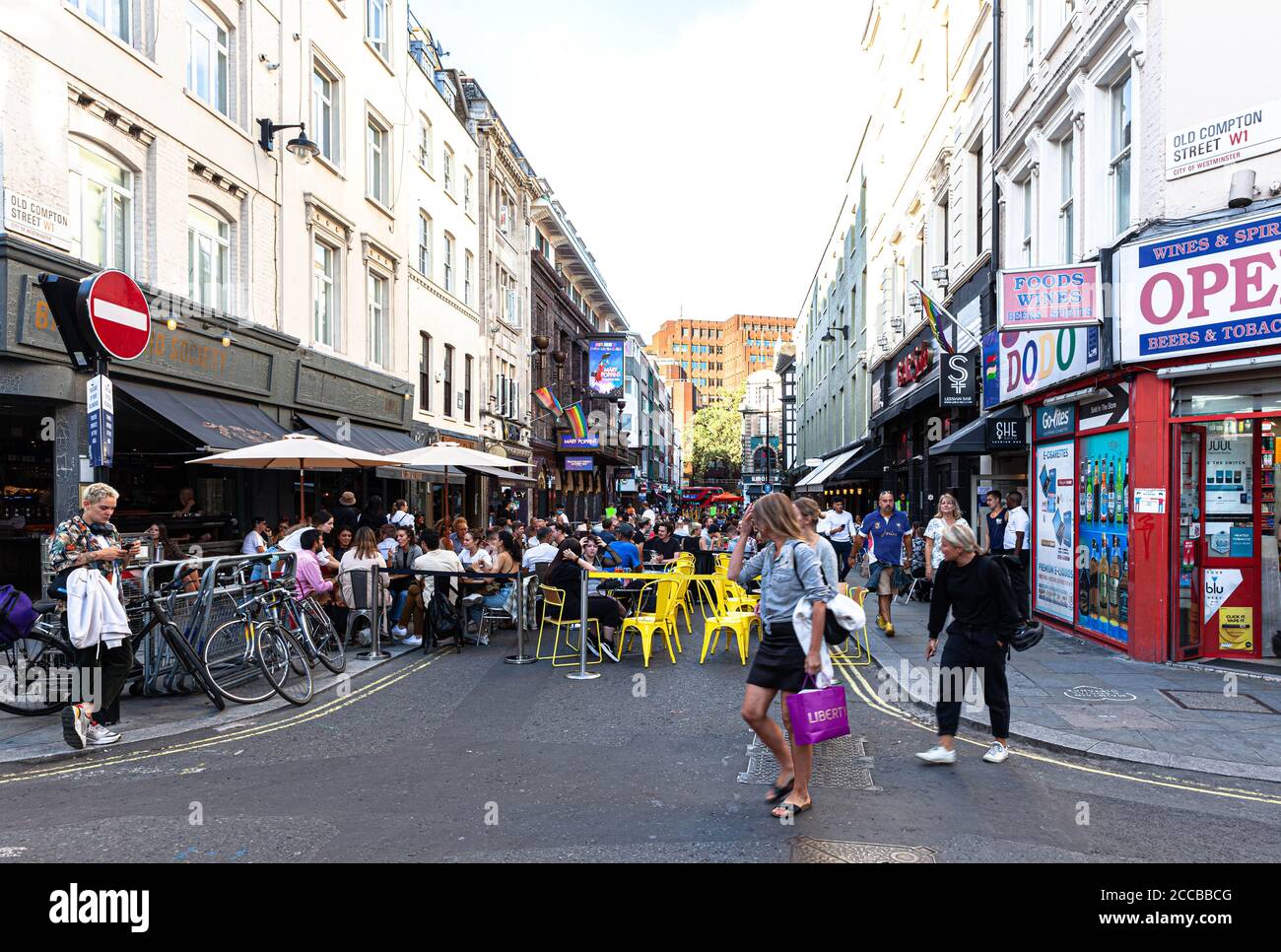 Customers dining al fresco on a pedestrianised street, Old Compton Street, Soho, London, UK
