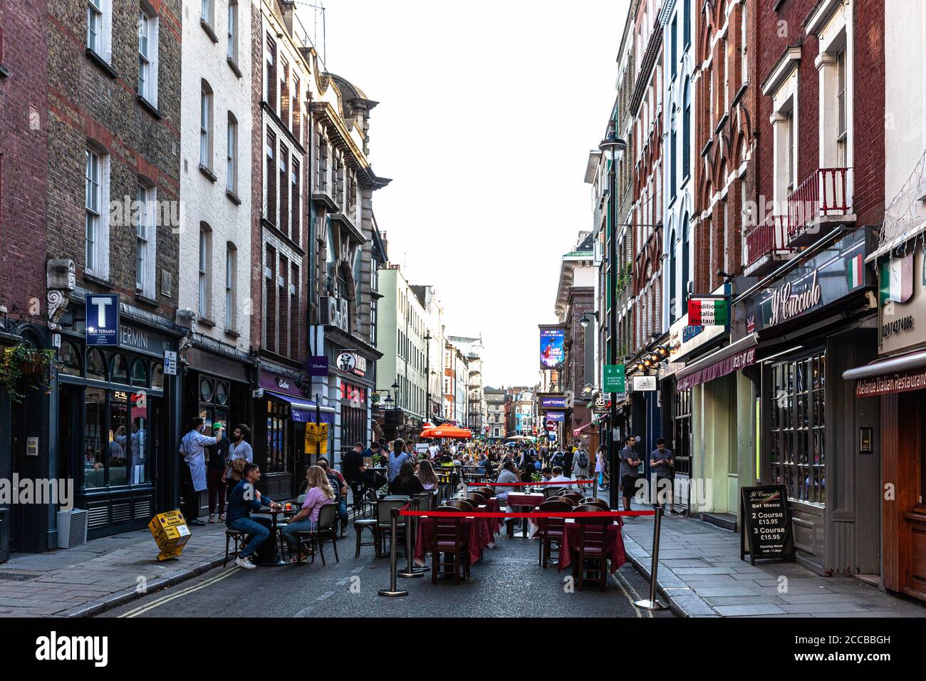 Customers dining al fresco on a pedestrianised street, Old Compton Street, Soho, London, UK