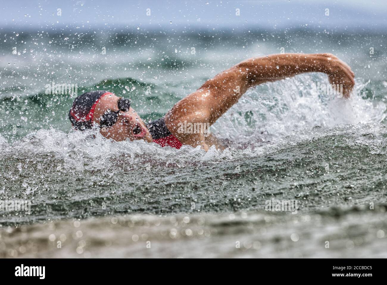 Triathlon swim tired swimmer swimming in ocean in wave and rain storm