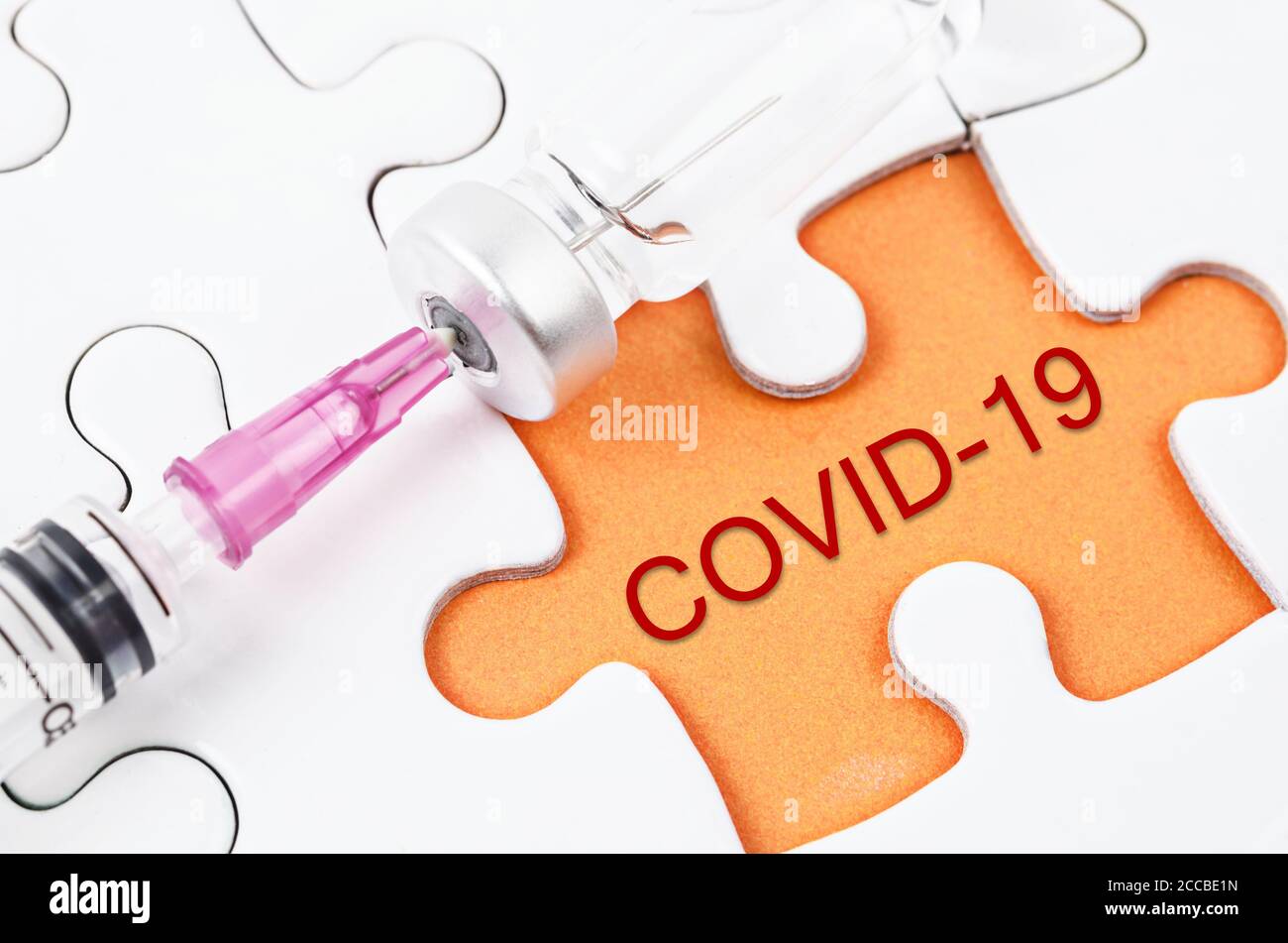 Vaccine and syringe injection with COVID-19 text on jigsaw. Prevention, immunization and treatment from corona virus infection.  Medicine infectious c Stock Photo