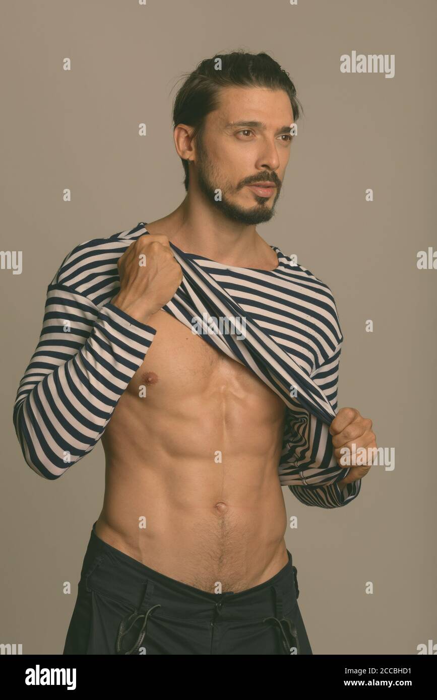 Studio shot of handsome man showing abs and thinking Stock Photo