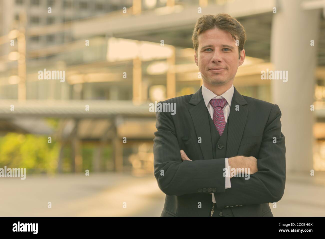 Businessman with arms crossed in front of modern building at Bangkok ...