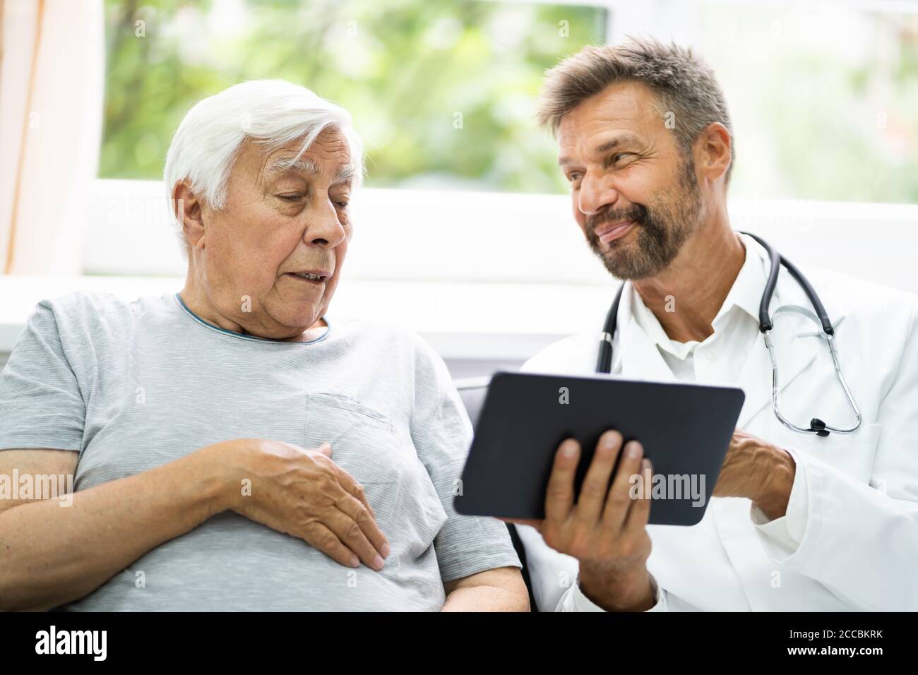 Home Care Elder Patient Looking At XRay Images Shown By His Doctor Stock Photo
