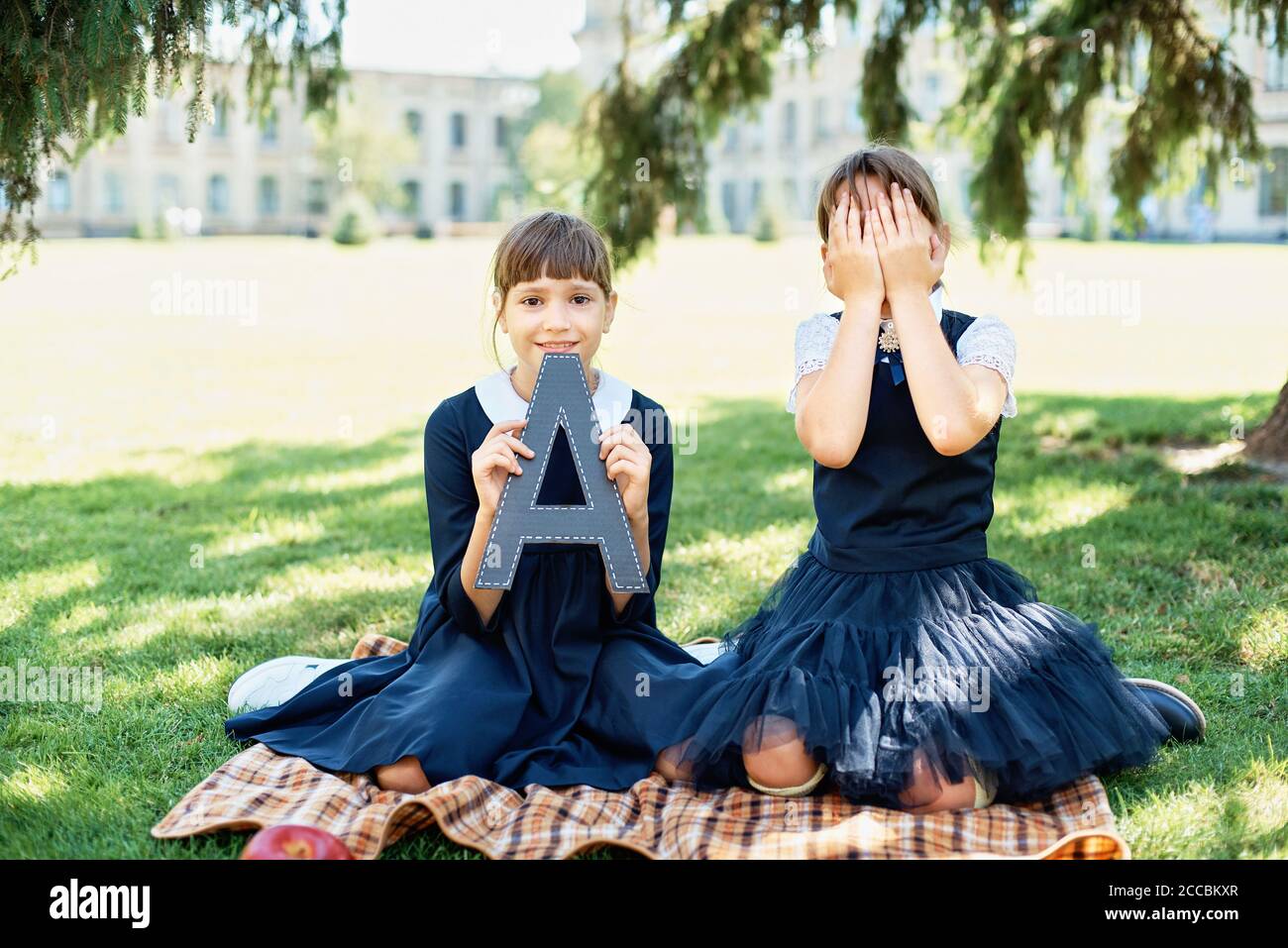 Portrait of two beautiful Schoolgirls on background school. Farewell Bell. day of knowledge. beginning of school year. Children with letter A Stock Photo