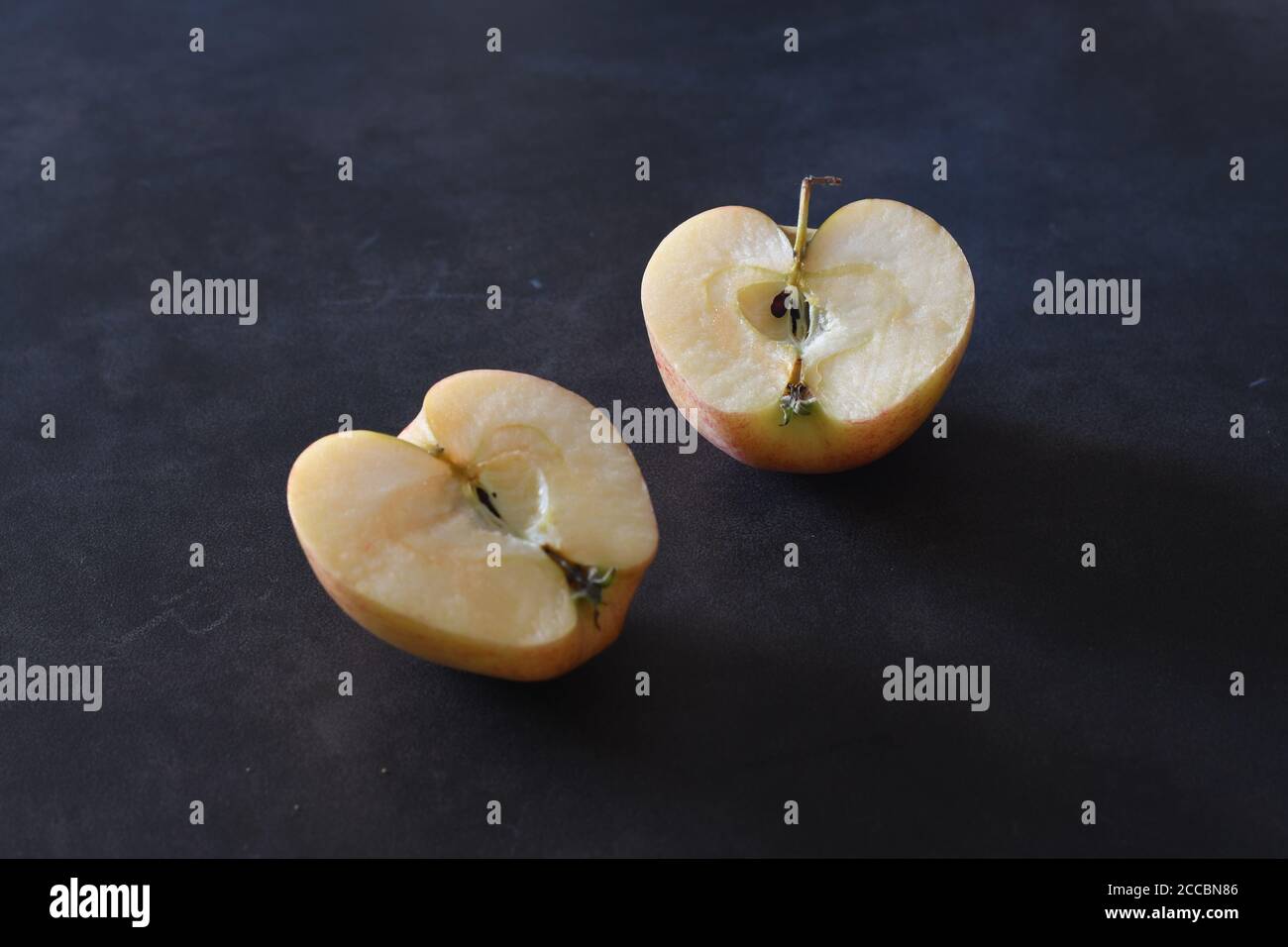 Small apple cut in two halves over a blackboard background Stock Photo