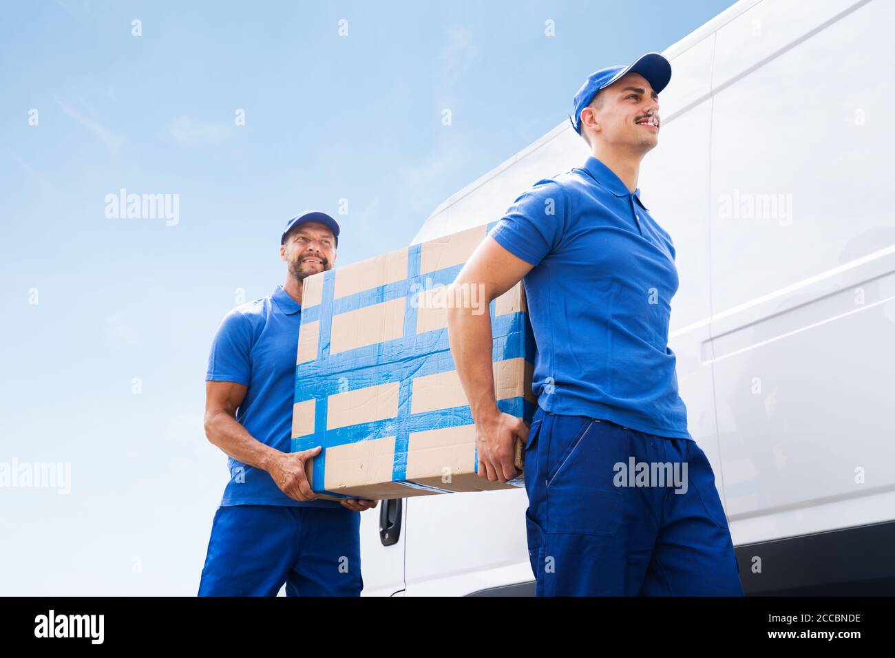 Delivery And Removal. 2 Movers Near Van. Side View Stock Photo