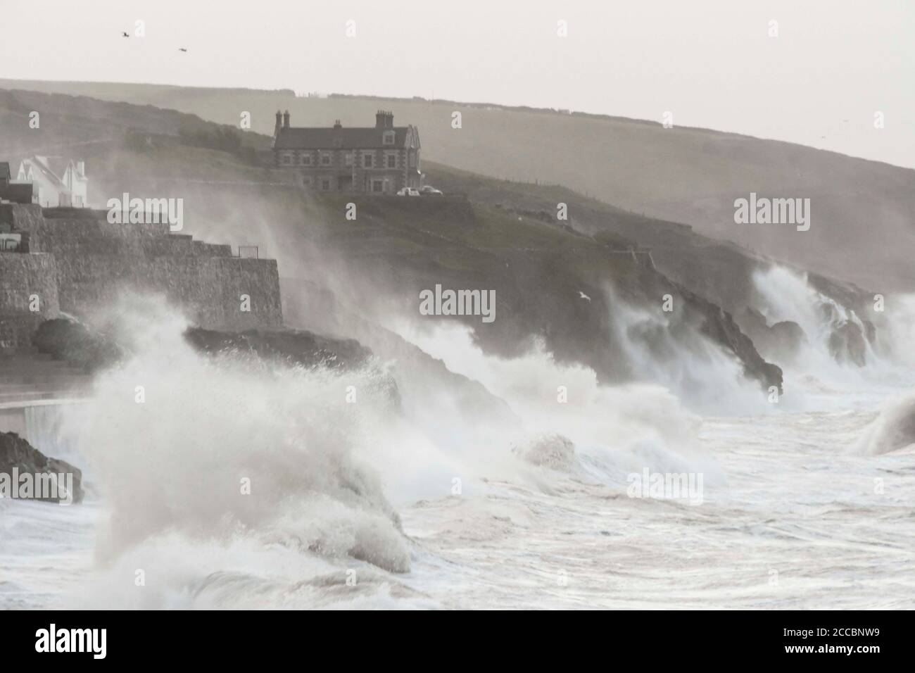 Porthleven, Cornwall, UK.  21st August 2020.  UK Weather.  Huge waves from Storm Ellen smash into the cliffs and coastal defences at Porthleven in Cornwall at sunrise during high tide on a morning of gale force winds from Storm Ellen.  Picture Credit: Graham Hunt/Alamy Live News Stock Photo