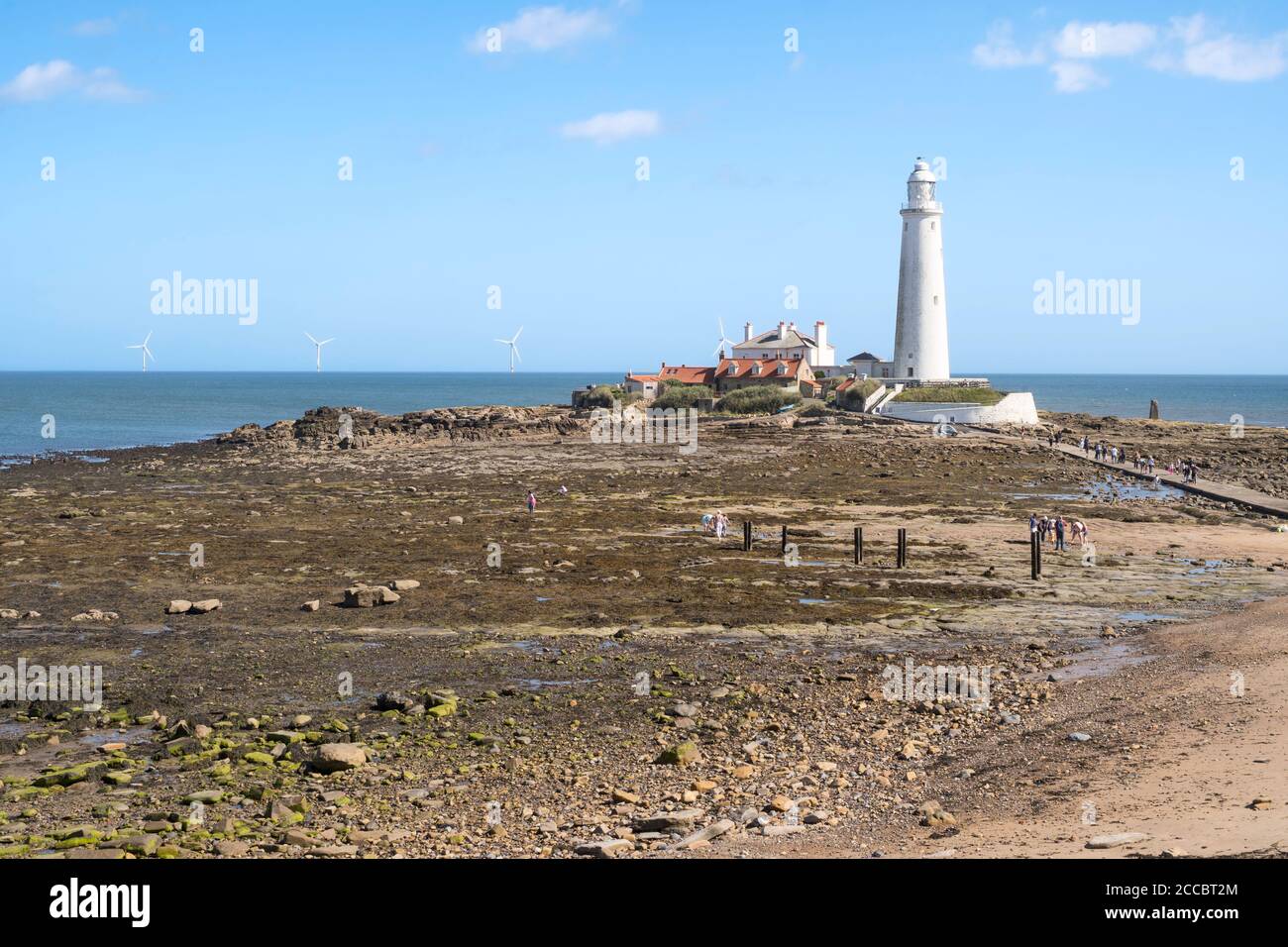 St Mary's island and lighthouse at low tide with people crossing the causeway at Whitley Bay, north east England, UK Stock Photo